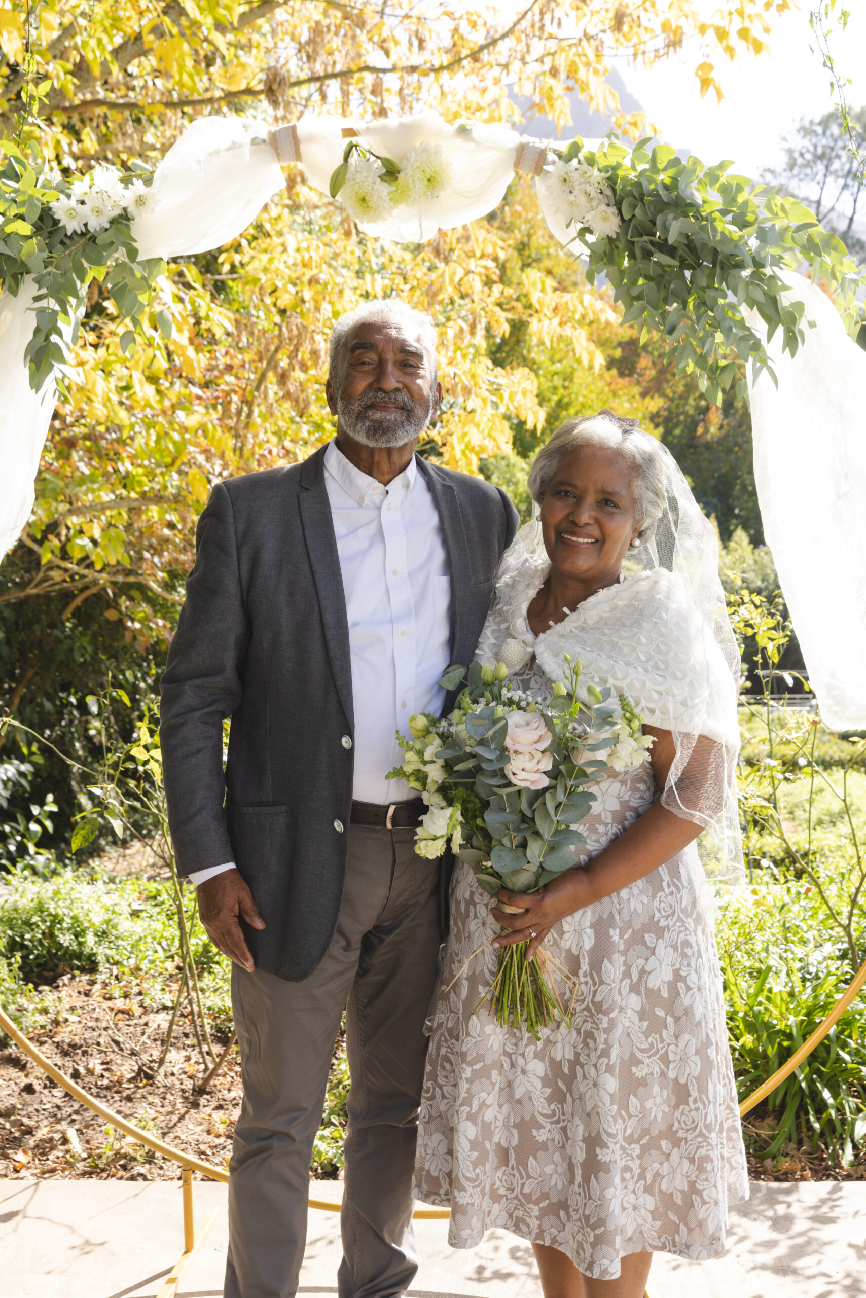Portrait of happy senior biracial bride and groom at sunny outdoor wedding ceremony. Marriage, romance, love, tradition, ceremony, summer, retirement and senior lifestyle, unaltered.