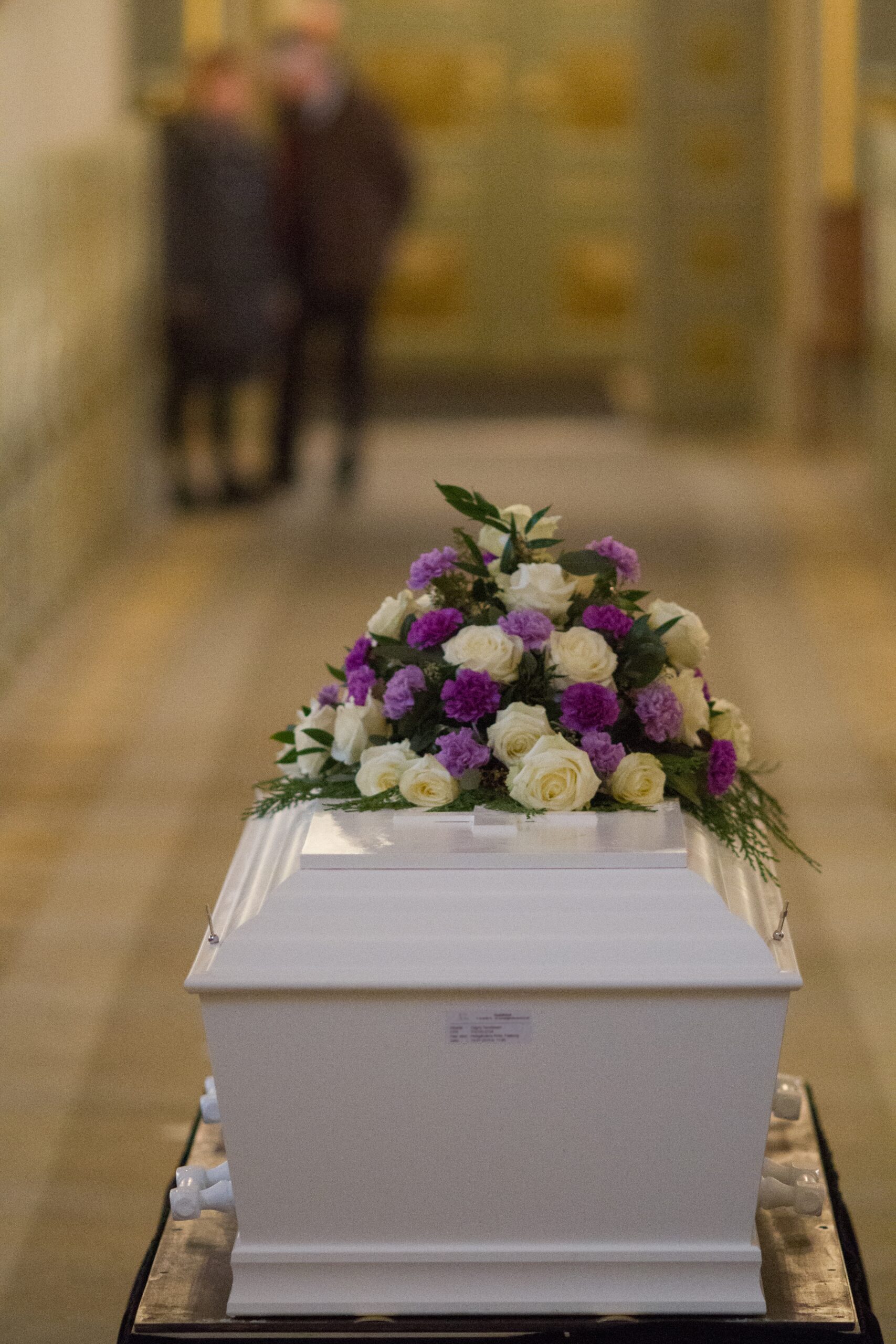 Vertical shot of a flower over a white casket with a blurred background